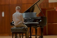 a young man playing a piano in an auditorium